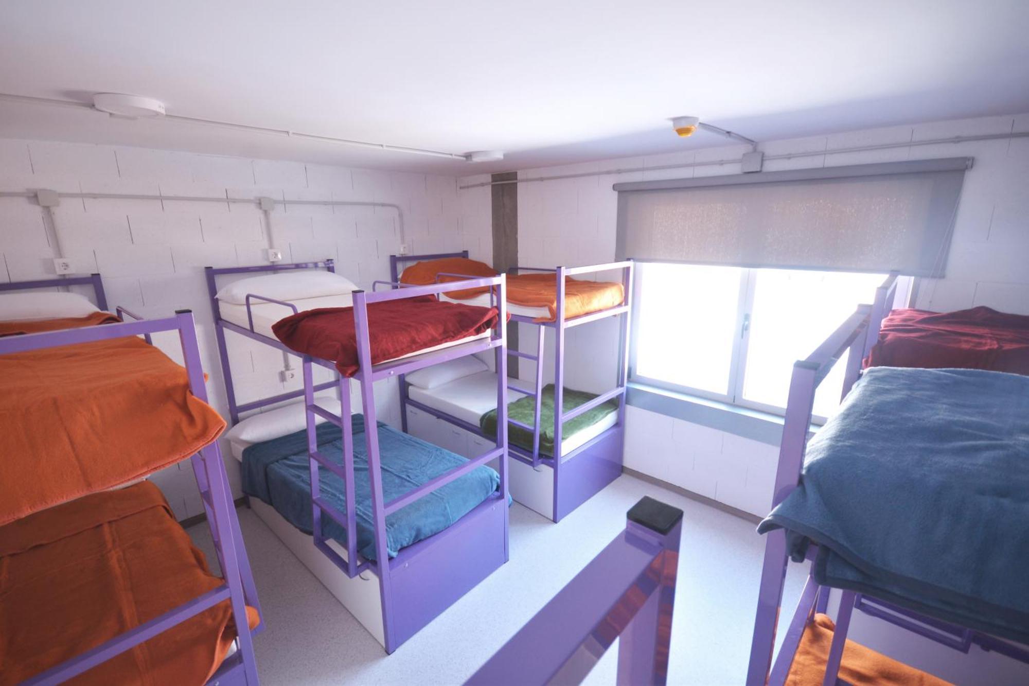Cama en habitación compartida mixta con 12 camas y baño compartido